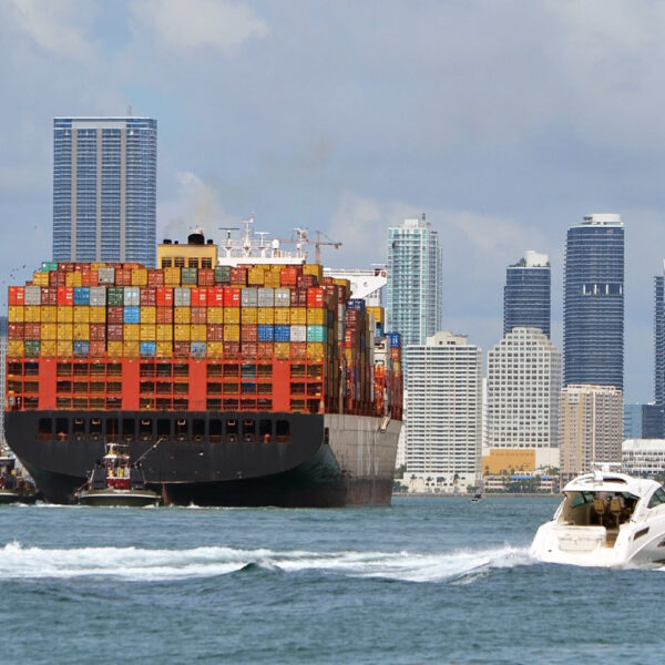 Container ship approaching cargo cranes at the Port of MiamiMiamiFlorida with downtown Miami skyline in the background.