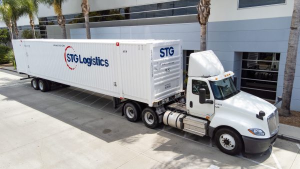Motor Carrier Success Capture - STG Truck and intermodal container in front of Warehouse.